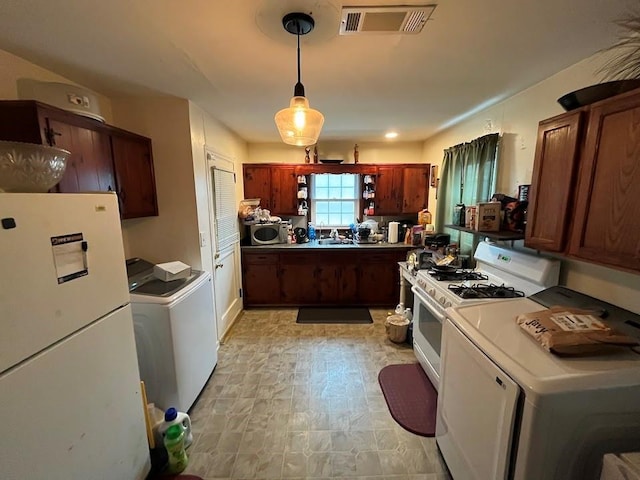 kitchen with pendant lighting, white appliances, washer / dryer, and sink