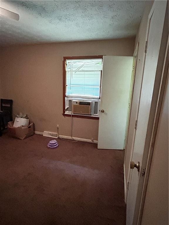 carpeted empty room featuring a textured ceiling and cooling unit