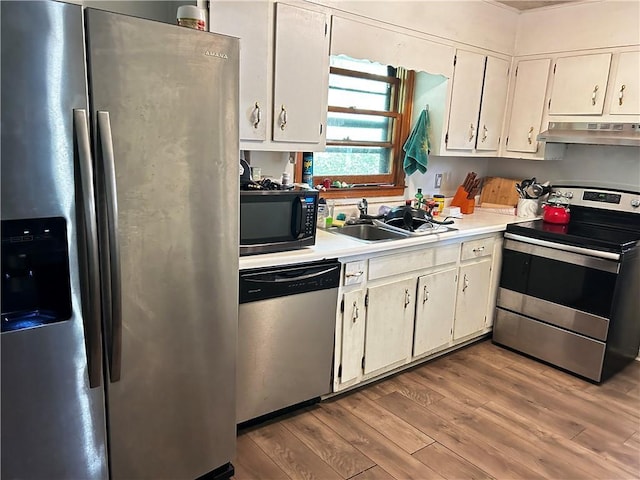 kitchen featuring white cabinets, sink, stainless steel appliances, and exhaust hood