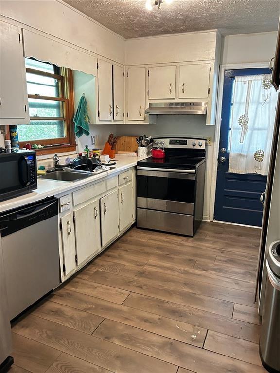 kitchen with sink, dark hardwood / wood-style floors, a textured ceiling, white cabinetry, and stainless steel appliances