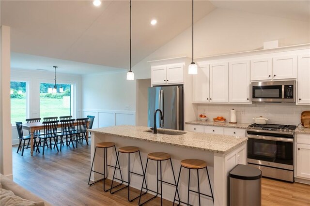 201 Advent Dr, Winder, GA 30680 - kitchen with appliances with stainless steel finishes, a sink, a kitchen breakfast bar, tasteful backsplash, and white cabinetry