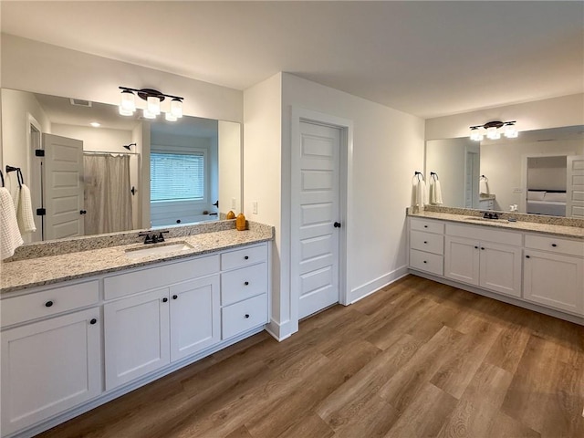 201 Advent Dr, Winder, GA 30680 - full bathroom featuring wood finished floors, two vanities, curtained shower, and baseboards