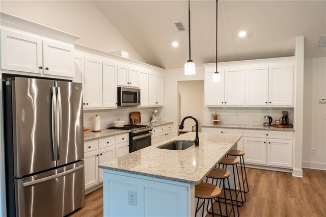 201 Advent Dr, Winder, GA 30680 - kitchen featuring appliances with stainless steel finishes, a sink, backsplash, a kitchen breakfast bar, and lofted ceiling