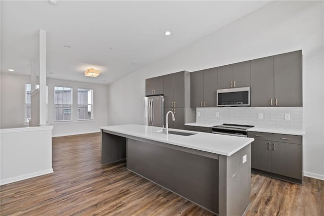 1227 Cushenberry Ln, Atlanta, GA 30318 - kitchen featuring a sink, stainless steel appliances, vaulted ceiling, backsplash, and a center island with sink