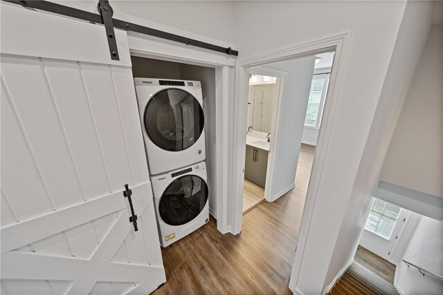 1227 Cushenberry Ln, Atlanta, GA 30318 - laundry room with a barn door, stacked washer / drying machine, wood finished floors, and healthy amount of natural light