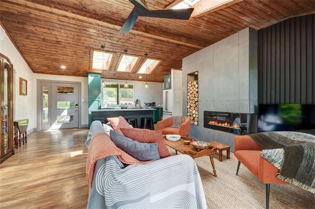 361 Rising Star Rd, Ellijay, GA 30536 - living room featuring a skylight, wooden ceiling, a tiled fireplace, a ceiling fan, and light wood finished floors
