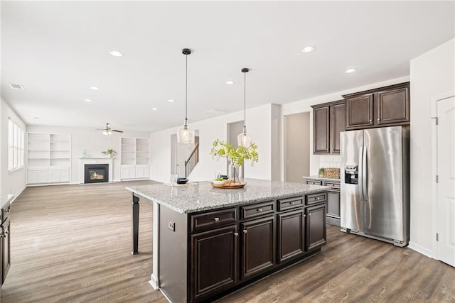 kitchen featuring stainless steel refrigerator with ice dispenser, a kitchen island, pendant lighting, and a kitchen bar