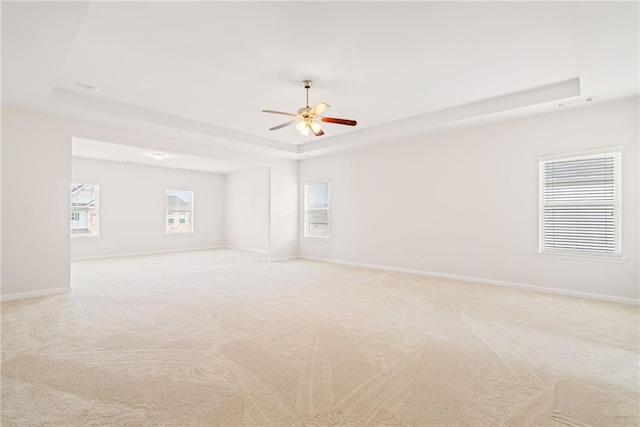 carpeted empty room featuring a tray ceiling and ceiling fan