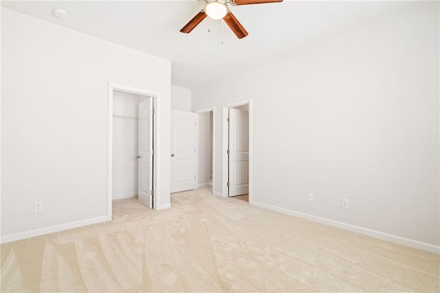 unfurnished bedroom with ceiling fan, a closet, a spacious closet, and light carpet