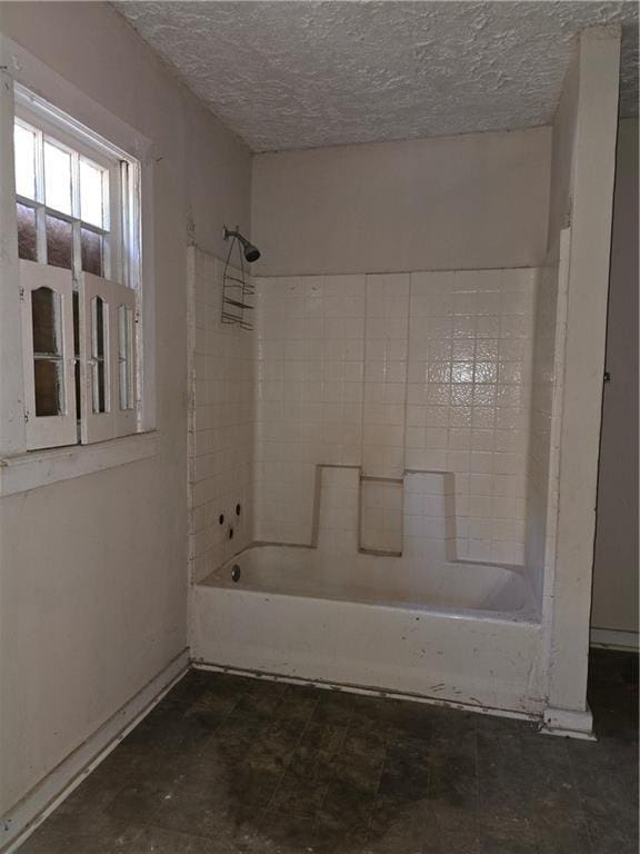 bathroom with tub / shower combination and a textured ceiling