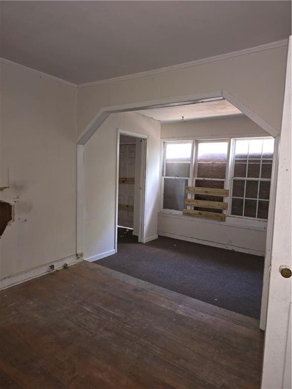 unfurnished room with baseboards, crown molding, and dark wood finished floors