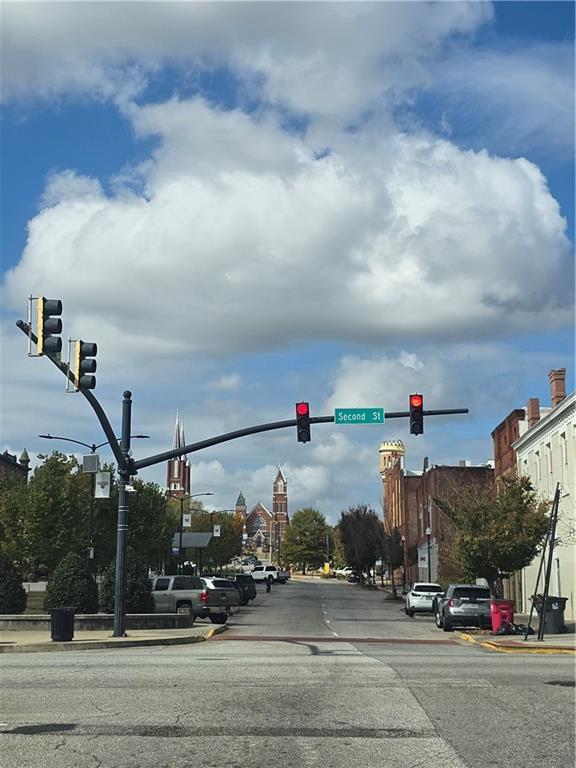 view of asphalt road with traffic lights, curbs, sidewalks, and street lights