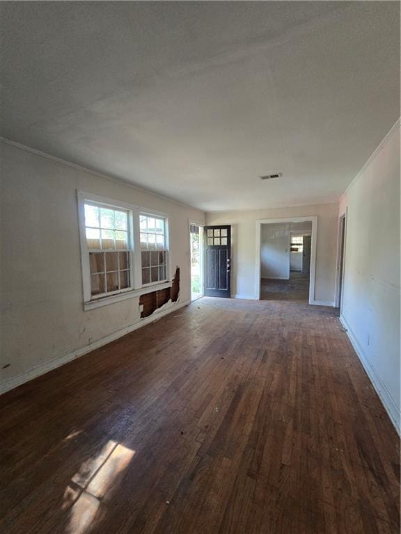 unfurnished living room with wood finished floors, ornamental molding, and baseboards