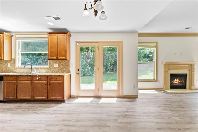 1492 Station Ridge Ct, Lawrenceville, GA 30045 - kitchen featuring a chandelier, brown cabinets, light wood finished floors, and backsplash