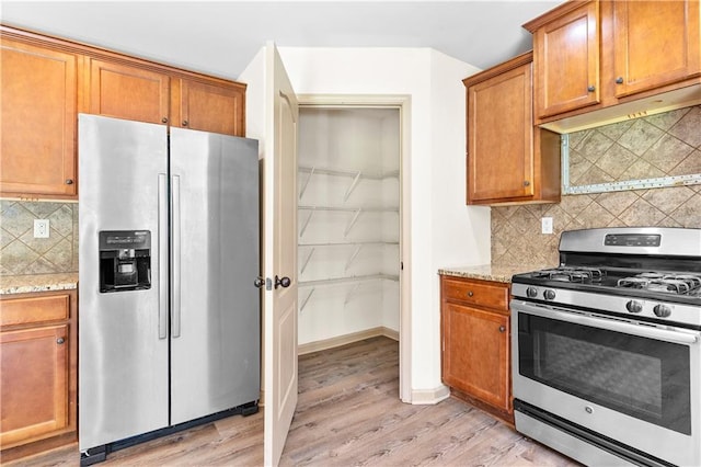 1492 Station Ridge Ct, Lawrenceville, GA 30045 - kitchen featuring appliances with stainless steel finishes, backsplash, light wood-style flooring, light stone countertops, and brown cabinets