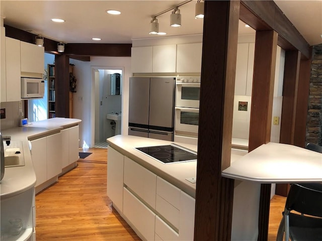 5015 Wright Bridge Rd, Cumming, GA 30028 - kitchen with freestanding refrigerator, black electric cooktop, white microwave, white cabinetry, and recessed lighting