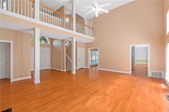 unfurnished living room with ceiling fan, hardwood / wood-style floors, and a high ceiling