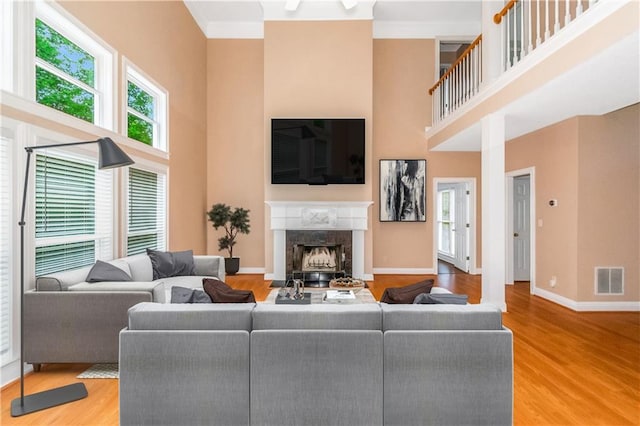 living room featuring hardwood / wood-style flooring, a fireplace, and a high ceiling