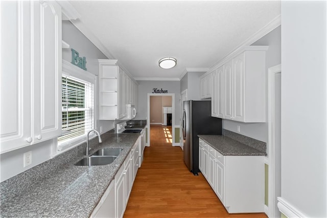 kitchen featuring stainless steel refrigerator, white cabinetry, sink, light hardwood / wood-style floors, and crown molding