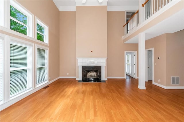 unfurnished living room featuring a towering ceiling, wood-type flooring, and a high end fireplace