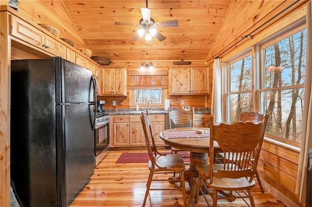 kitchen with vaulted ceiling, gas stove, black fridge, and light brown cabinetry