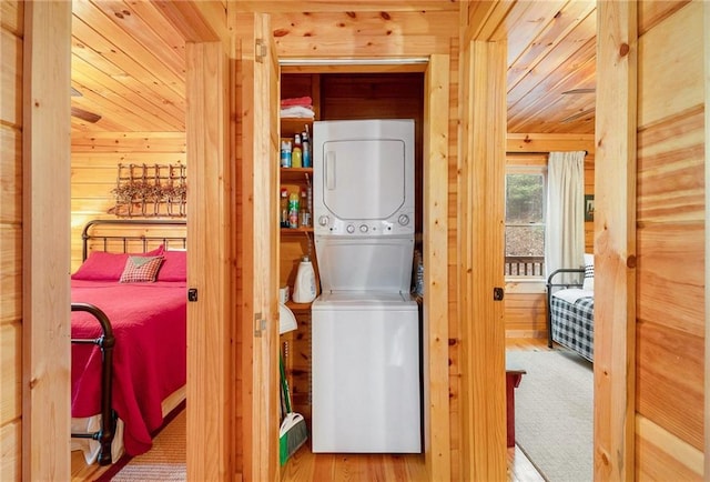 clothes washing area with wood ceiling, stacked washer / drying machine, and wood walls