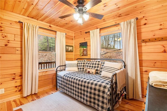 sitting room with wooden walls, wooden ceiling, light hardwood / wood-style floors, and ceiling fan