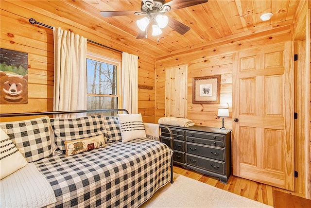 sitting room featuring ceiling fan, light hardwood / wood-style floors, wood ceiling, and wood walls