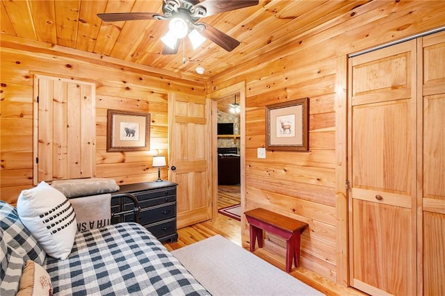 bedroom with light wood-type flooring, wooden ceiling, and wood walls