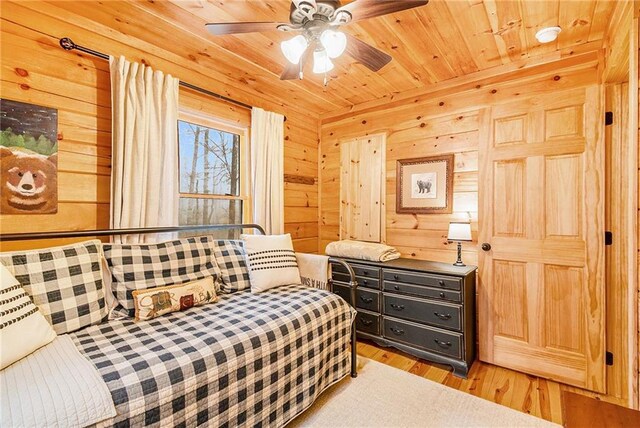 bedroom featuring light hardwood / wood-style flooring, wooden ceiling, and wood walls