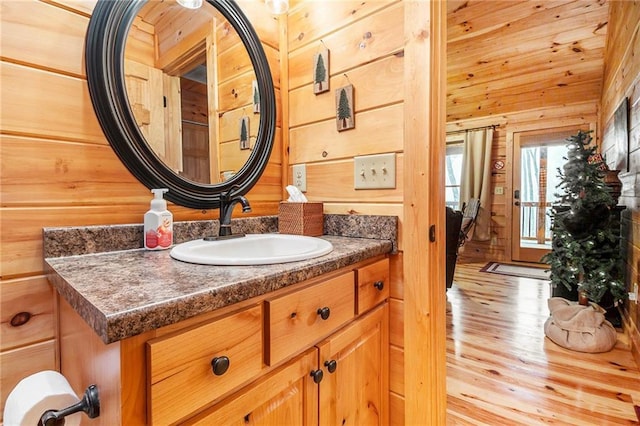 bathroom with hardwood / wood-style flooring, vanity, and wood walls