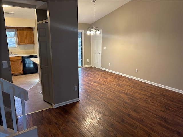 kitchen featuring an inviting chandelier, hanging light fixtures, black dishwasher, wood-type flooring, and vaulted ceiling