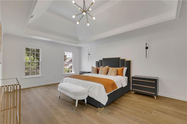 bedroom with light hardwood / wood-style floors, a tray ceiling, and an inviting chandelier