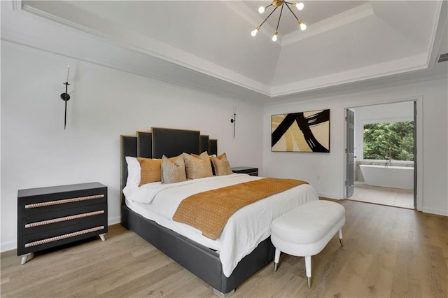 bedroom featuring a tray ceiling, an inviting chandelier, light wood-type flooring, crown molding, and ensuite bathroom