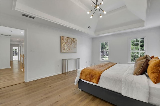 bedroom featuring light wood-type flooring, crown molding, an inviting chandelier, and a raised ceiling