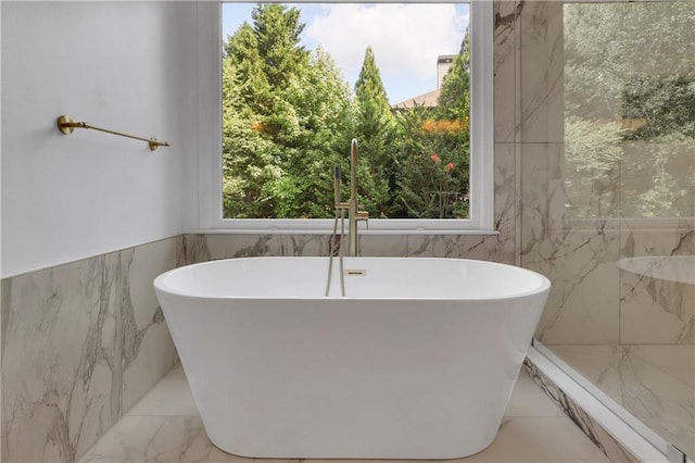 bathroom with a bathing tub and tile walls