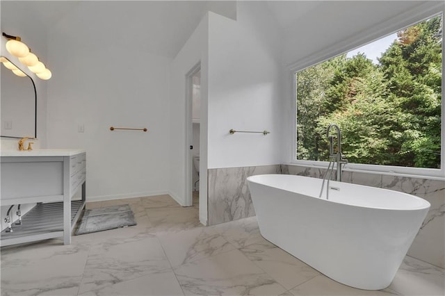 bathroom featuring a tub to relax in, tile walls, lofted ceiling, and vanity