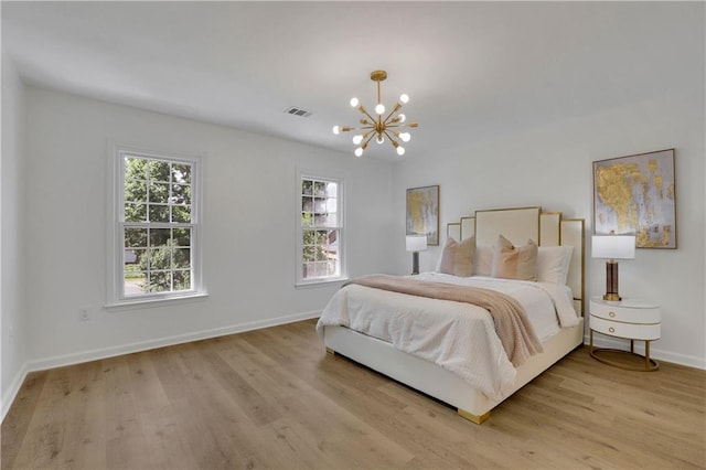 bedroom with an inviting chandelier and light hardwood / wood-style flooring