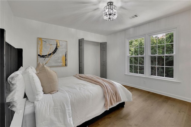 bedroom featuring a notable chandelier and hardwood / wood-style flooring