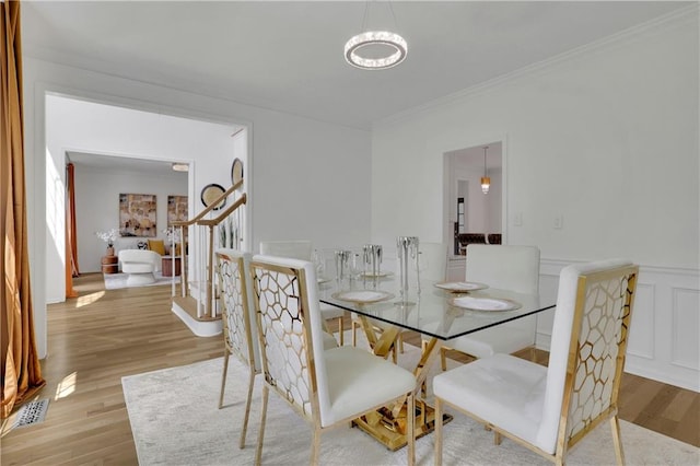 dining space featuring light wood-type flooring and crown molding