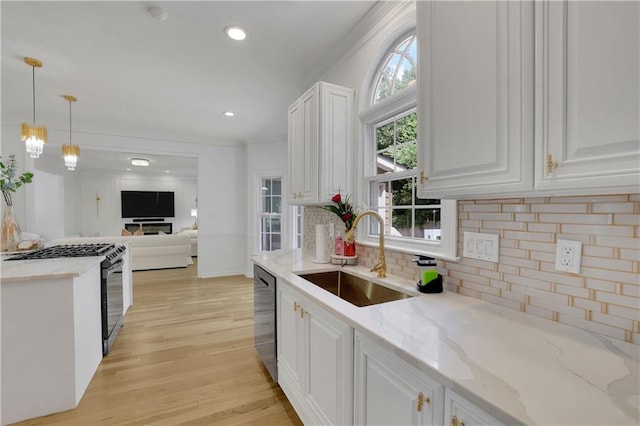 kitchen featuring hanging light fixtures, white cabinetry, stainless steel appliances, sink, and plenty of natural light