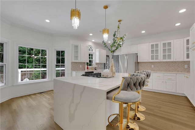 kitchen featuring light hardwood / wood-style floors, a center island, white cabinetry, decorative backsplash, and stainless steel fridge