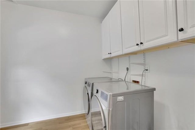 laundry room with washing machine and dryer, light hardwood / wood-style floors, and cabinets