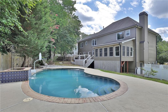 view of swimming pool featuring a wooden deck, a sunroom, and a patio area