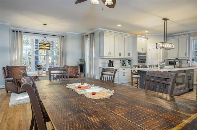 dining room with crown molding, sink, ceiling fan, and light hardwood / wood-style floors