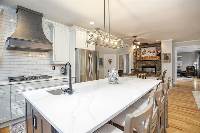 kitchen with a kitchen island, decorative light fixtures, custom range hood, and appliances with stainless steel finishes