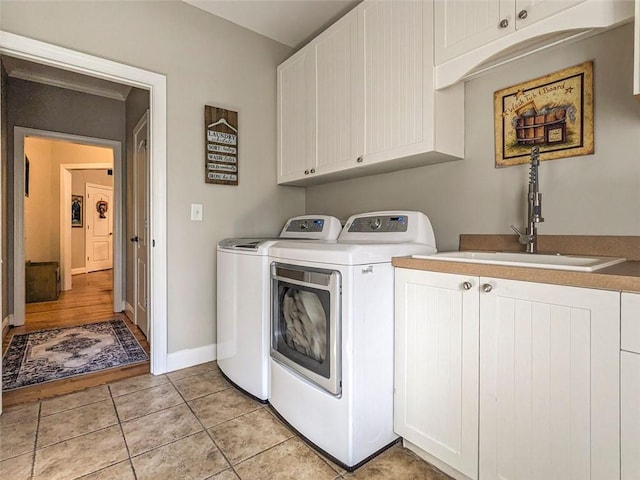 clothes washing area with cabinets, independent washer and dryer, light tile patterned floors, and sink