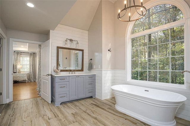 bathroom with an inviting chandelier, vanity, a healthy amount of sunlight, and wood-type flooring