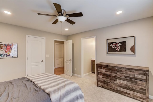 bedroom with light carpet, ensuite bath, and ceiling fan