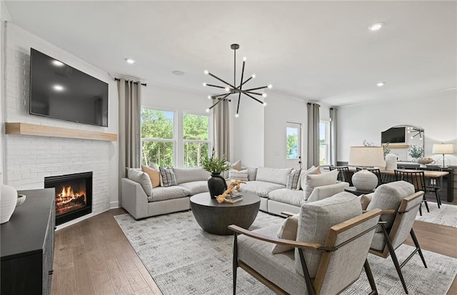 living room featuring a fireplace, wood finished floors, an inviting chandelier, and recessed lighting